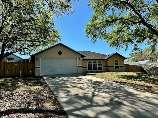 ranch-style home featuring concrete driveway, fence, a garage, and stucco siding