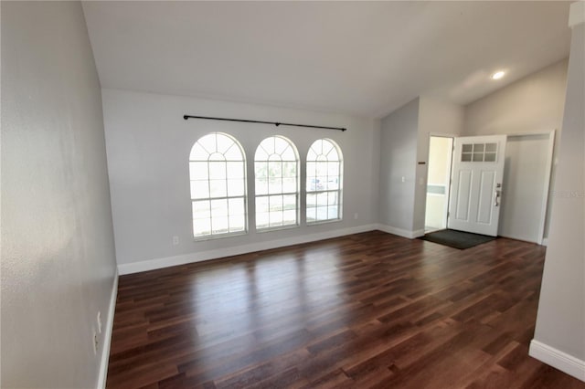 foyer entrance with dark wood-type flooring, baseboards, and vaulted ceiling