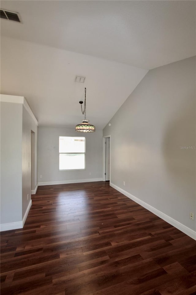 empty room with visible vents, lofted ceiling, dark wood-type flooring, and baseboards