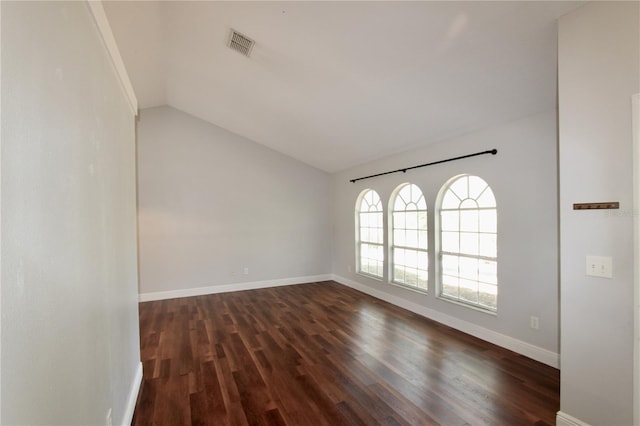 empty room featuring lofted ceiling, baseboards, visible vents, and dark wood-type flooring