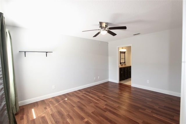 unfurnished room featuring ceiling fan, visible vents, baseboards, and dark wood finished floors