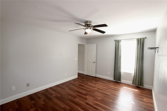 unfurnished room with dark wood finished floors, a textured ceiling, and baseboards