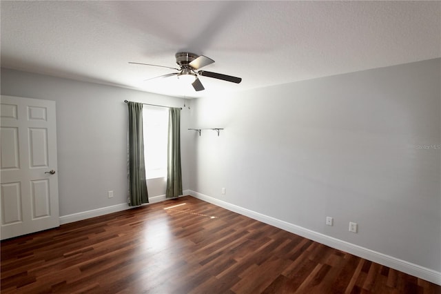 empty room with dark wood finished floors, ceiling fan, and baseboards