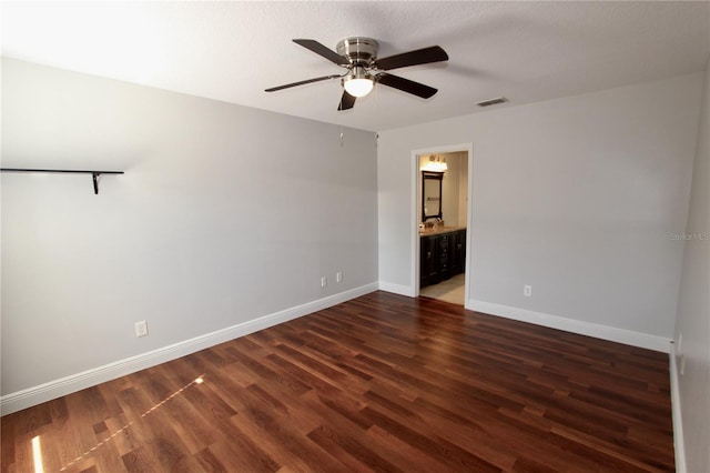 spare room with dark wood finished floors, visible vents, ceiling fan, and baseboards