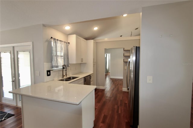 kitchen with a sink, tasteful backsplash, appliances with stainless steel finishes, a peninsula, and vaulted ceiling