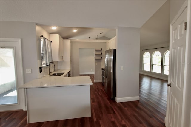 kitchen with light countertops, lofted ceiling, freestanding refrigerator, white cabinetry, and a sink