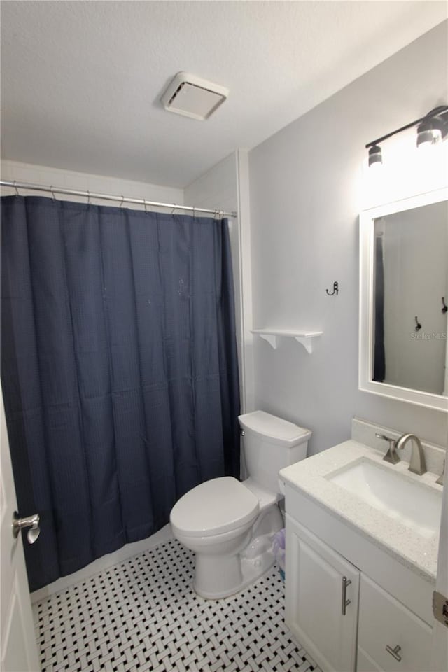 full bath featuring visible vents, toilet, vanity, a shower with curtain, and a textured ceiling