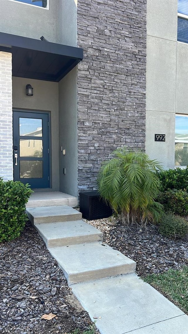 doorway to property featuring stucco siding and brick siding