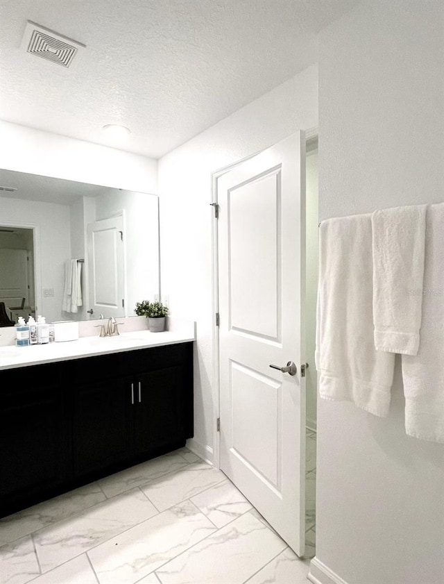 bathroom with visible vents, baseboards, vanity, marble finish floor, and a textured ceiling