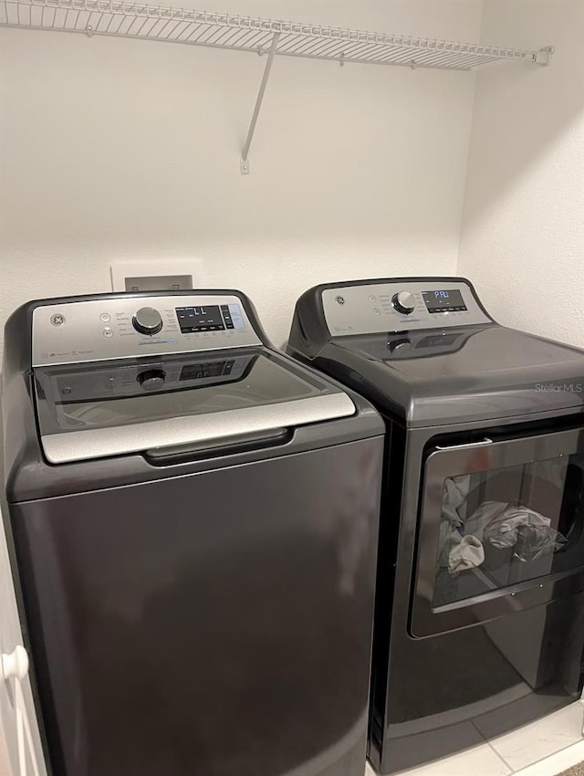 laundry room featuring washing machine and clothes dryer, laundry area, and tile patterned flooring