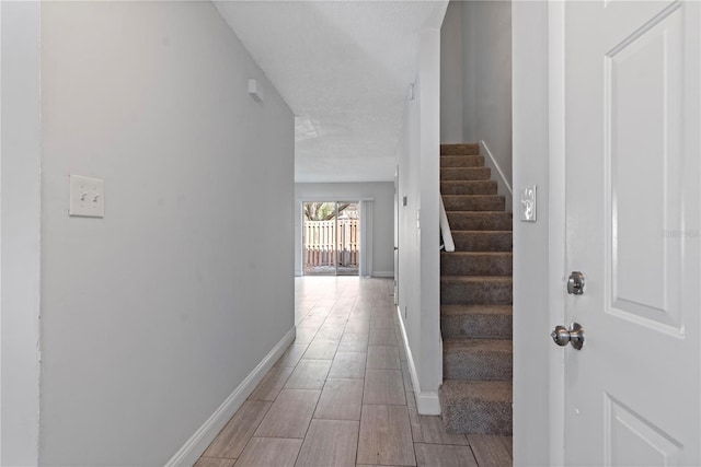 interior space featuring a textured ceiling, stairway, baseboards, and wood finish floors