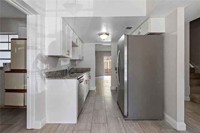 kitchen with visible vents, wood tiled floor, stone countertops, appliances with stainless steel finishes, and white cabinetry