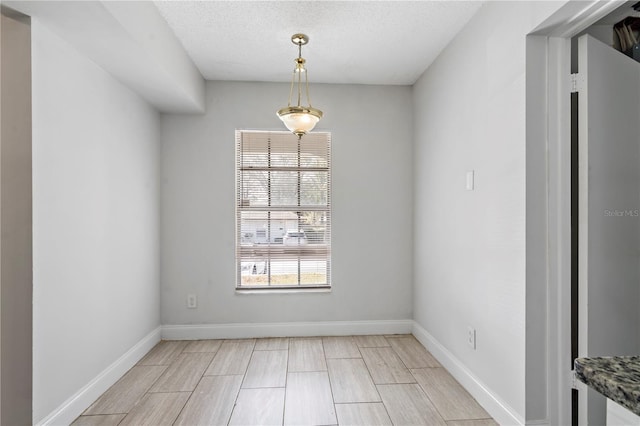 unfurnished dining area featuring baseboards and a textured ceiling