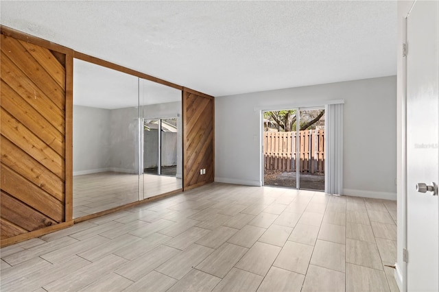 interior space featuring wooden walls, baseboards, and a textured ceiling