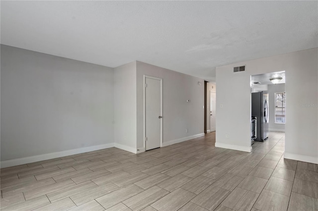 unfurnished room with visible vents, baseboards, and a textured ceiling