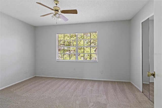 carpeted empty room featuring a ceiling fan, baseboards, and a textured ceiling