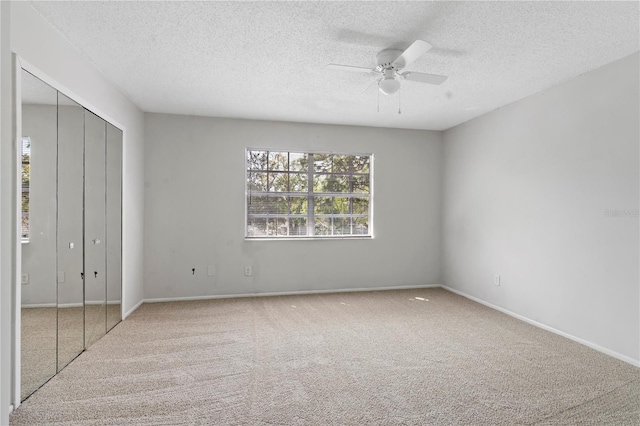 unfurnished bedroom with a textured ceiling, a closet, carpet floors, baseboards, and ceiling fan