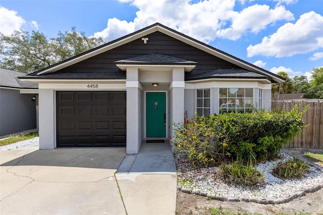 view of front of property featuring driveway, roof with shingles, a garage, and fence