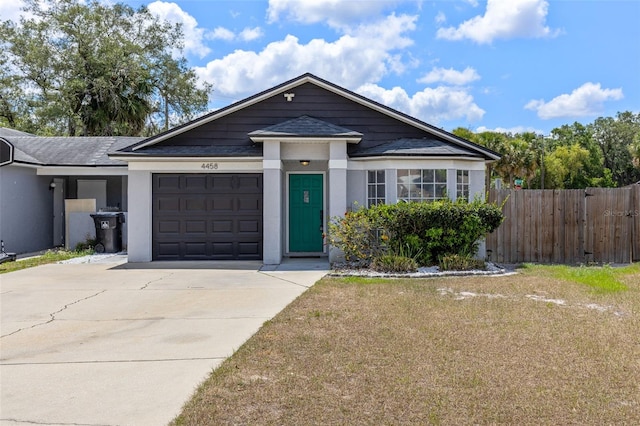 view of front of home with stucco siding, fence, roof with shingles, concrete driveway, and a garage