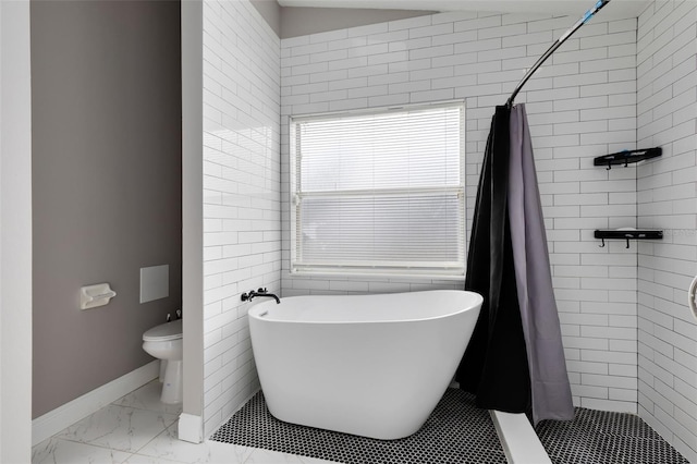 bathroom featuring a shower stall, baseboards, a freestanding bath, toilet, and marble finish floor