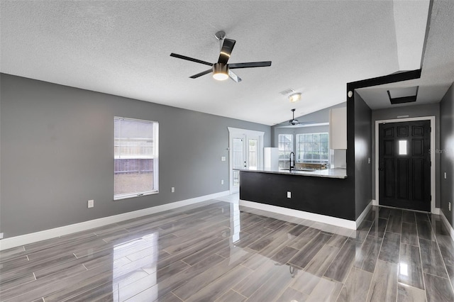 interior space featuring baseboards, wood tiled floor, lofted ceiling, a ceiling fan, and a sink