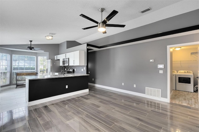 kitchen with visible vents, washing machine and clothes dryer, open floor plan, and stainless steel microwave