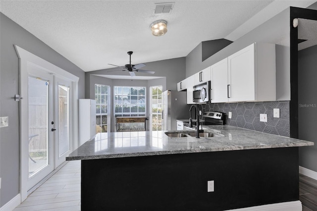 kitchen featuring visible vents, appliances with stainless steel finishes, a peninsula, and vaulted ceiling