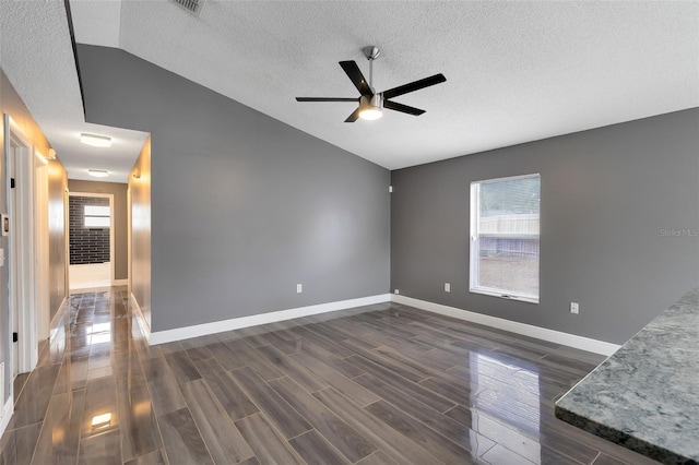 unfurnished living room with a textured ceiling, baseboards, ceiling fan, dark wood-style flooring, and vaulted ceiling