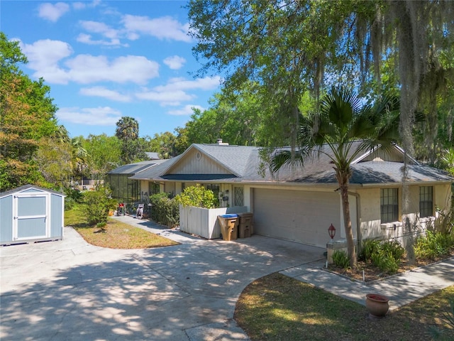 ranch-style house with a storage unit, concrete driveway, an attached garage, and a shingled roof