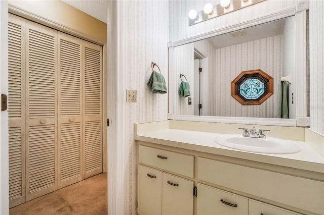 bathroom with vanity and wallpapered walls