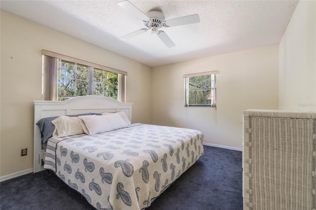 bedroom with ceiling fan, baseboards, dark colored carpet, and a textured ceiling