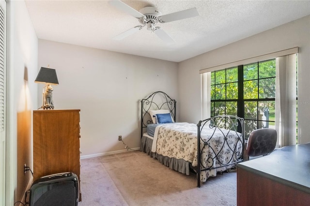 bedroom with baseboards, light carpet, a textured ceiling, and a ceiling fan