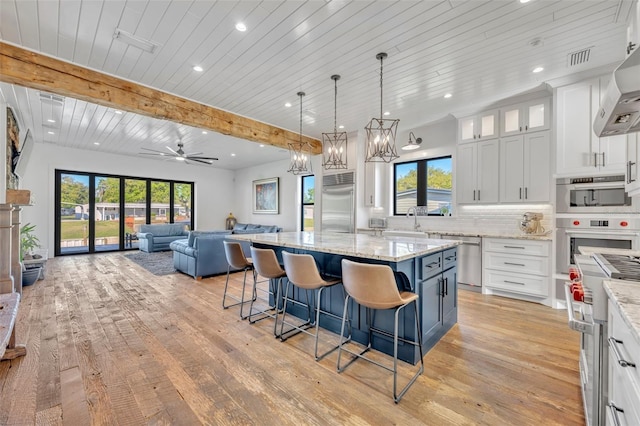 kitchen featuring beamed ceiling, tasteful backsplash, open floor plan, white cabinetry, and appliances with stainless steel finishes