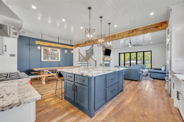 kitchen with hanging light fixtures, light wood-style flooring, ventilation hood, and ceiling fan