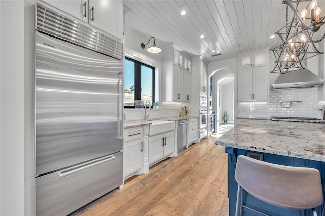 kitchen with white cabinetry, arched walkways, appliances with stainless steel finishes, and a sink