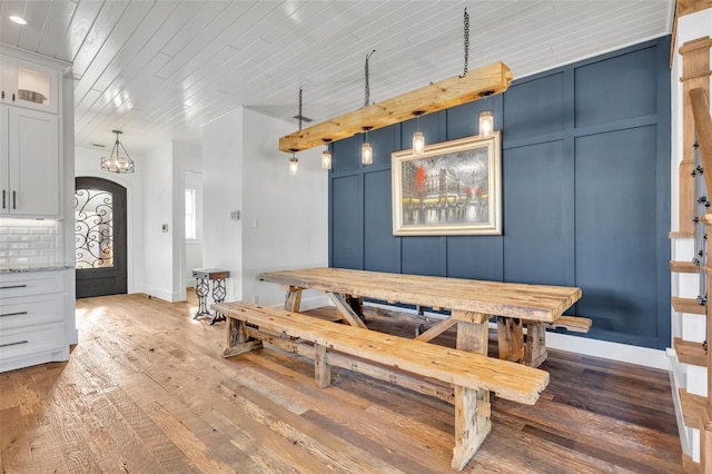 dining area featuring baseboards, wood ceiling, arched walkways, a decorative wall, and wood-type flooring