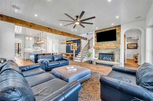 living area with light wood-type flooring, beam ceiling, wooden ceiling, arched walkways, and a ceiling fan