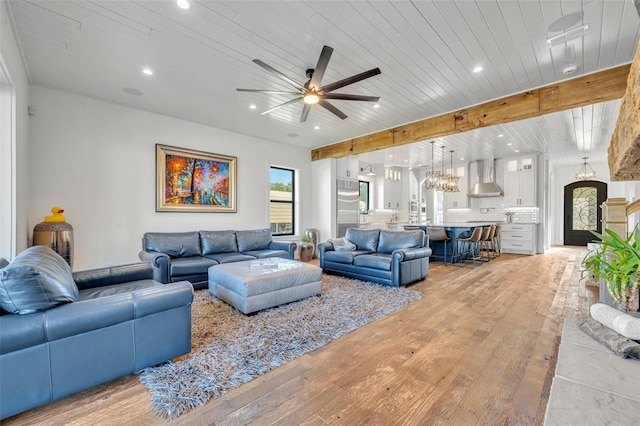 living room featuring recessed lighting, beamed ceiling, ceiling fan with notable chandelier, and light wood-type flooring