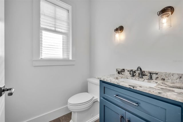 half bath featuring vanity, toilet, wood finished floors, and baseboards