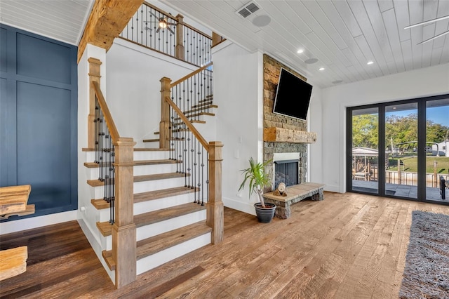 stairway with baseboards, recessed lighting, wooden ceiling, a fireplace, and wood finished floors