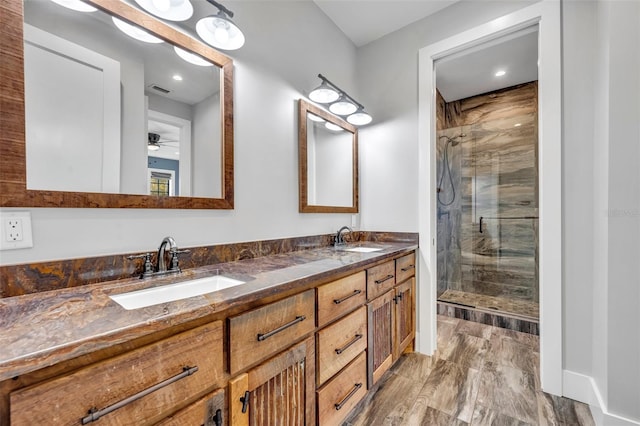 bathroom with double vanity, a stall shower, a ceiling fan, and a sink