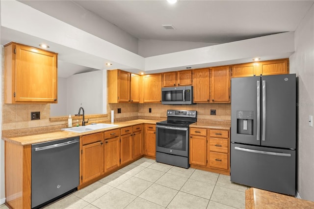 kitchen featuring lofted ceiling, light countertops, appliances with stainless steel finishes, and a sink