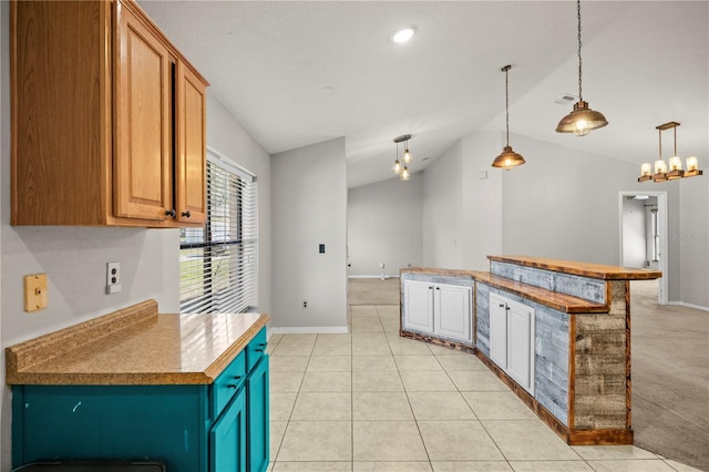 kitchen featuring decorative light fixtures, baseboards, light tile patterned flooring, and vaulted ceiling