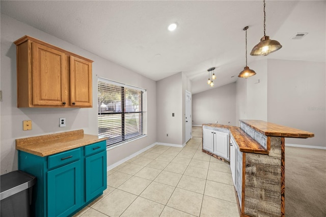 kitchen featuring visible vents, decorative light fixtures, baseboards, light tile patterned floors, and lofted ceiling