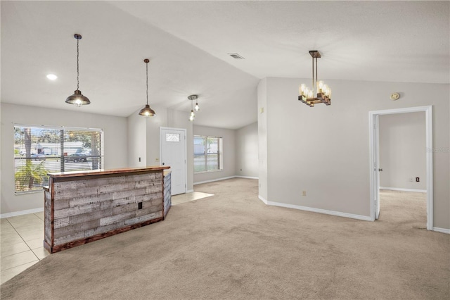 kitchen featuring baseboards, lofted ceiling, hanging light fixtures, light colored carpet, and a chandelier