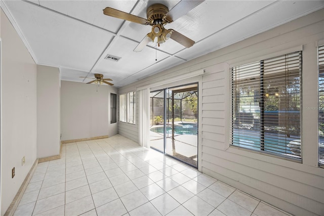 spare room with light tile patterned flooring, visible vents, ceiling fan, and a sunroom