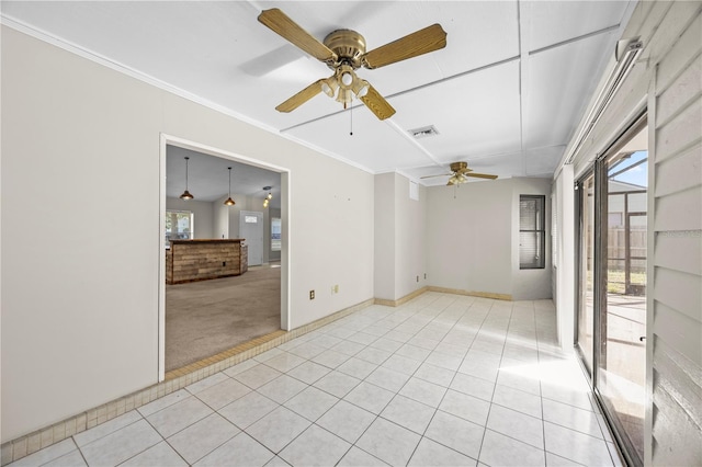 spare room featuring light tile patterned floors, a ceiling fan, visible vents, and ornamental molding