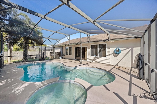 view of pool featuring a patio area, glass enclosure, a pool with connected hot tub, and fence