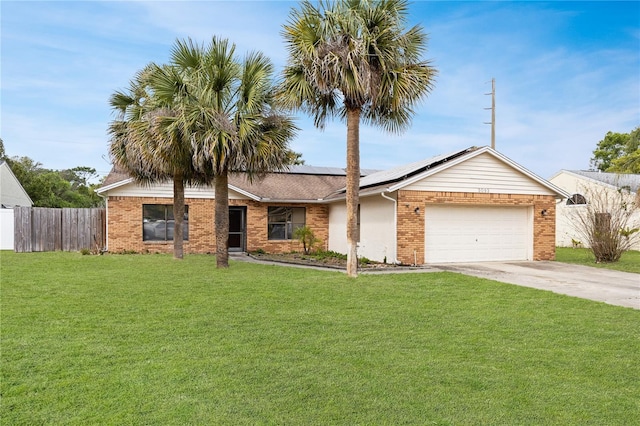 ranch-style house featuring solar panels, a front yard, fence, and driveway