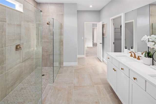 bathroom with vanity, baseboards, recessed lighting, a tile shower, and a walk in closet